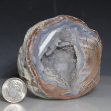 Load image into Gallery viewer, Geode with internal crystal structure next to a U.S. dime for scale on a dark background