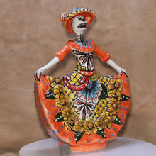 Load image into Gallery viewer, Decorative figure of a skeleton in an orange dress with floral patterns on a brown background with quarter for scale