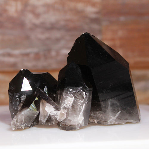Black crystal formation on a white surface with a blurred brown background Smoky Black Quartz Ron Coleman Mining