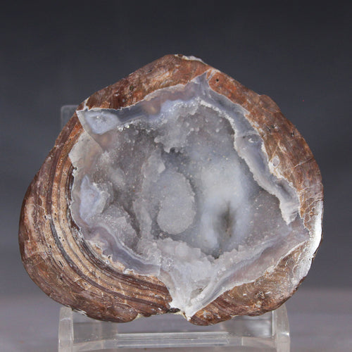 Geode with agate interior on a clear stand against a dark background