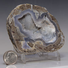 Load image into Gallery viewer, Geode with internal crystal structure on a stand, next to a dime for scale, against a gray background
