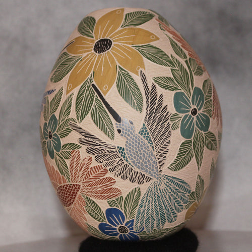 Decorative stone with floral and bird design on a gray background