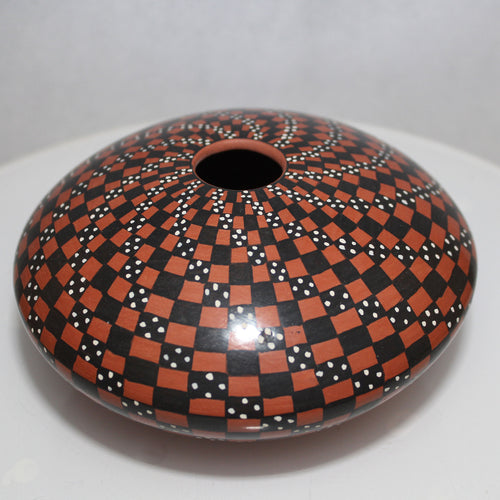 Decorative vase with a black and orange checkered pattern on a white background