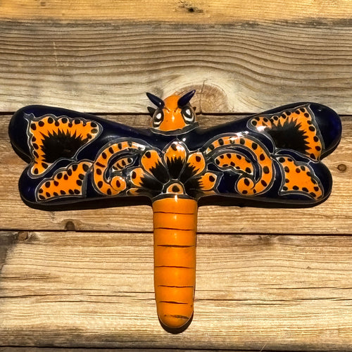 Decorative wall art with a dragonfly design on a wooden surface