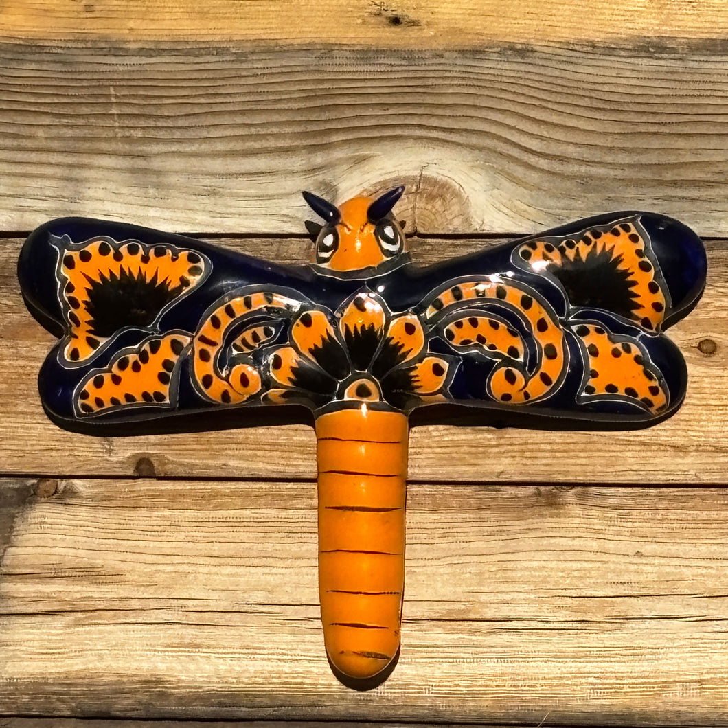 Decorative wall art with a dragonfly design on a wooden surface